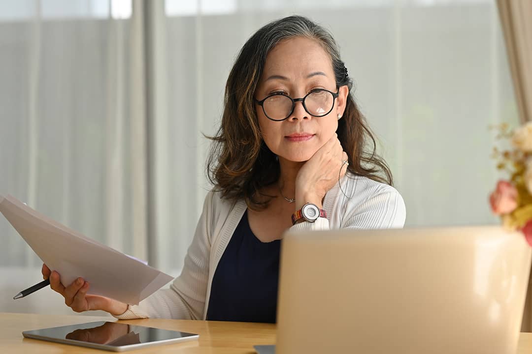 A senior woman reviewing financial documents at home.